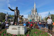 Guests watch a show near a statue of Walt Disney and Micky Mouse in front of the Cinderella Cas ...