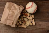 A bag of peanuts and a baseball on an old wooden bench at the ballpark. (Getty Images)