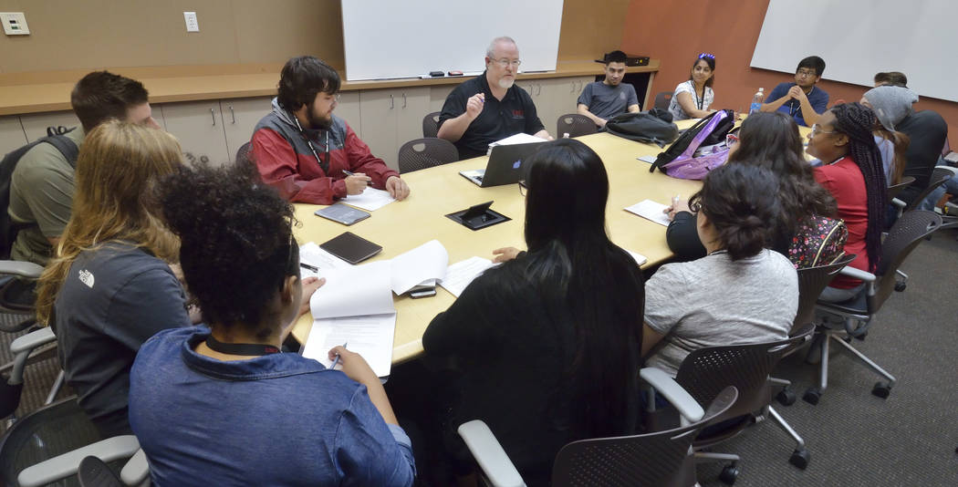 Lecturer Darwin Morgan, background center, talks with students during a briefing for a simulate ...