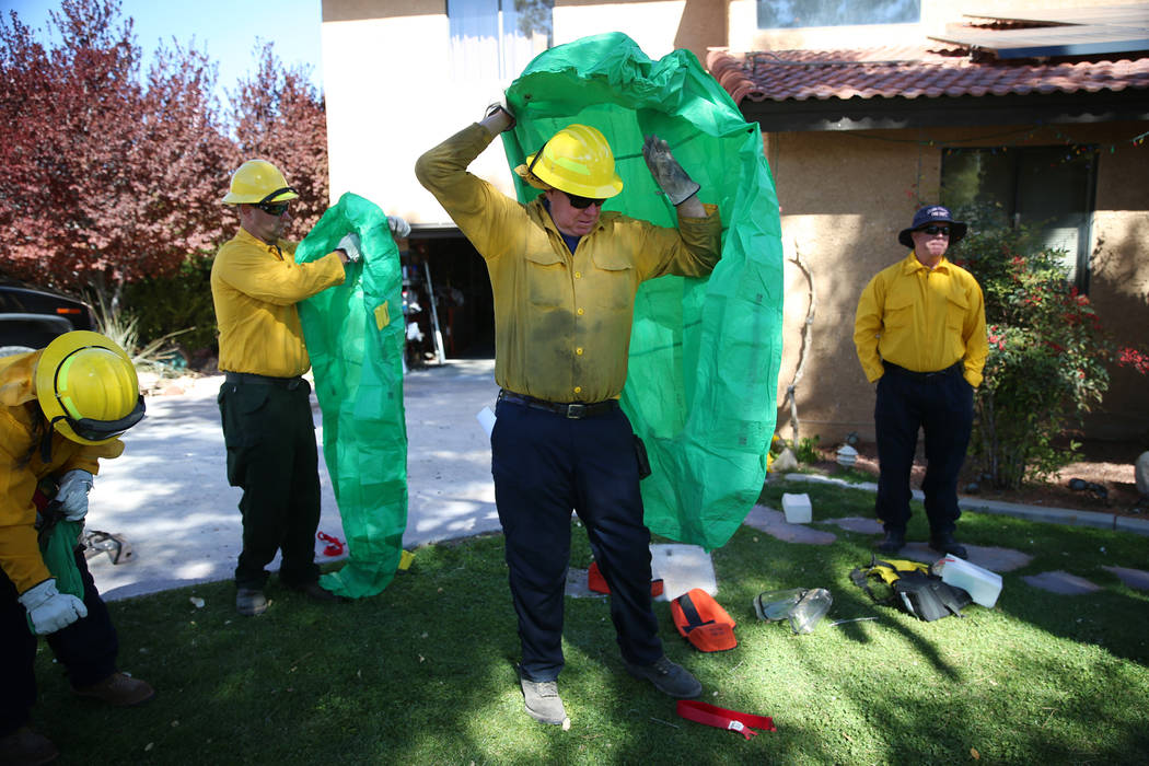 Dennis Lovell, center, engine boss and firefighter at Mt. Charleston, takes cover under a fire ...