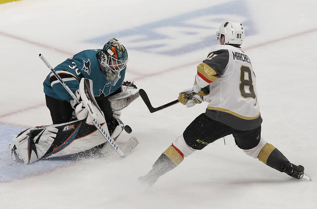 San Jose Sharks goaltender Aaron Dell, left, defends a shot attempt by Vegas Golden Knights cen ...