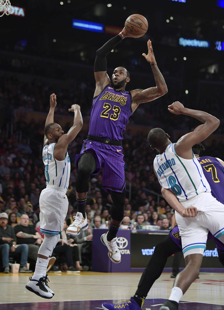 Los Angeles Lakers forward LeBron James, center, goes up for a dunk as Charlotte Hornets guard ...