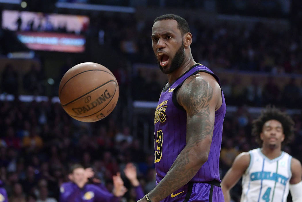 Los Angeles Lakers forward LeBron James, left, yells after dunking as Charlotte Hornets guard D ...