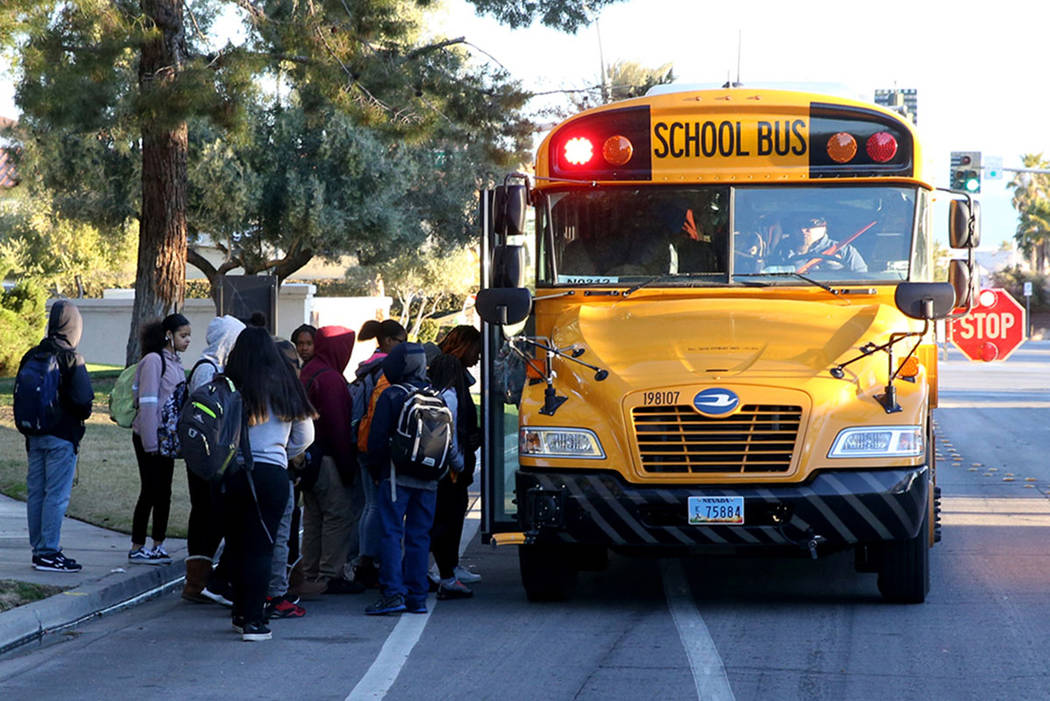 Students board the school bus on Soaring Gulls Drive near Cheyenne Avenue at Desert Shores Vill ...