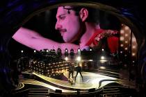 An image of Freddie Mercury appears on screen as Brian May, left, and Adam Lambert of Queen per ...