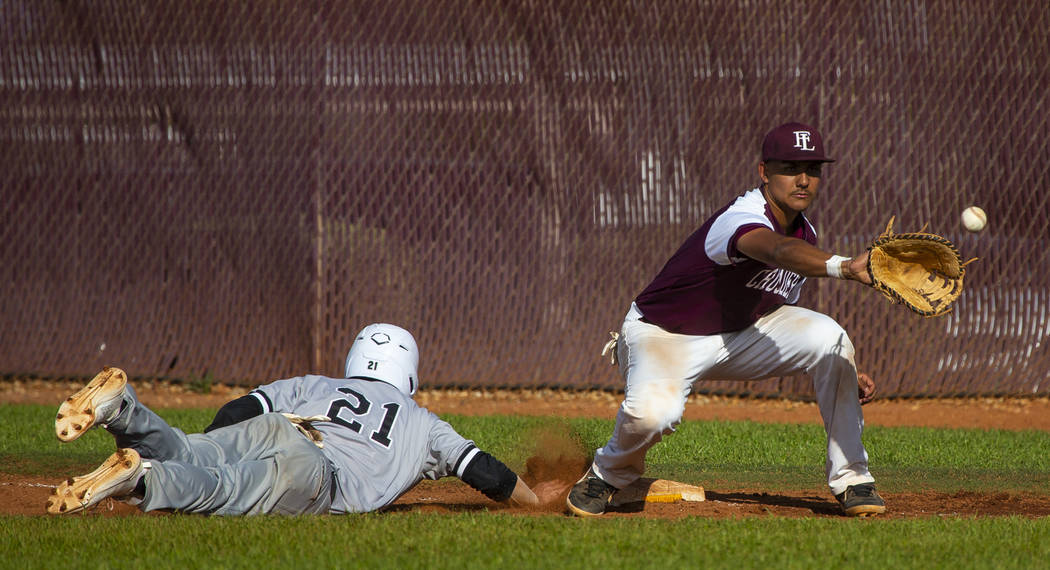 Palo Verde's Josiah Cromwick (21) dives back to first base ahead of a throw to Faith Lutheran's ...