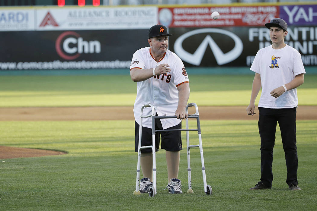 FILE - In this April 16, 2015, file photo, Bryan Stow, center, throws out the ceremonial first ...