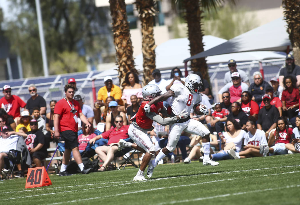 UNLV Rebels running back Charles Williams (8) runs the ball under pressure from defensive back ...