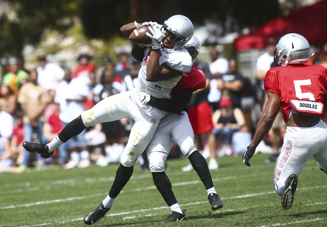 UNLV Rebels wide receiver Jeremy Clark (18) keeps hold of a reception under pressure from defen ...