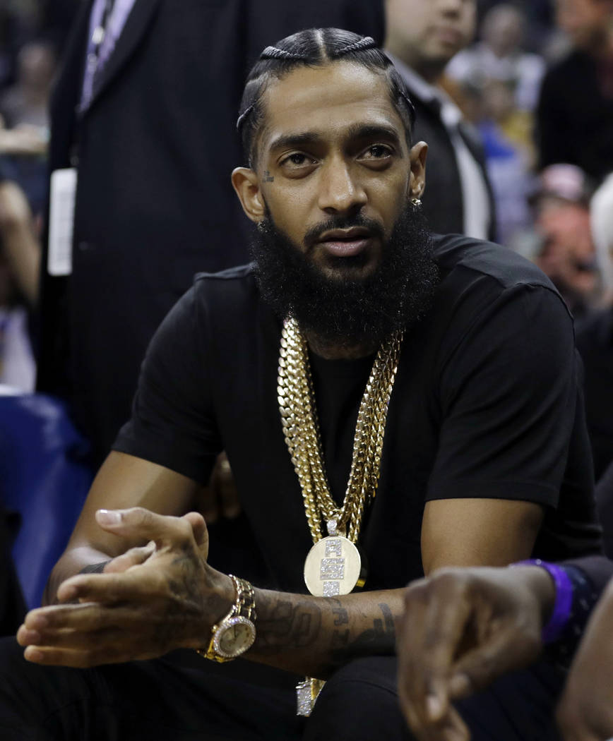 In this March 29, 2018, file photo, rapper Nipsey Hussle watches an NBA basketball game between ...
