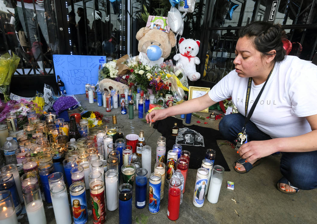 Jennifer Chavez lights candles at a makeshift memorial in front of the Marathon Clothing store ...