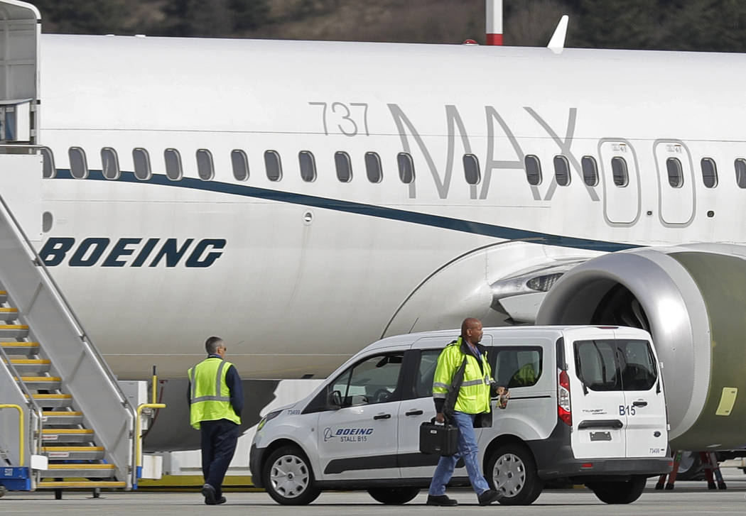 Workers walk next to a Boeing 737 MAX 8 airplane parked at Boeing Field, in Seattle on March 14 ...