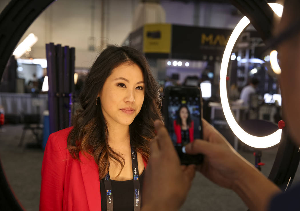 Nicki Sun of Los Angeles poses under an LED ring light at the Came-Tv booth during the final da ...