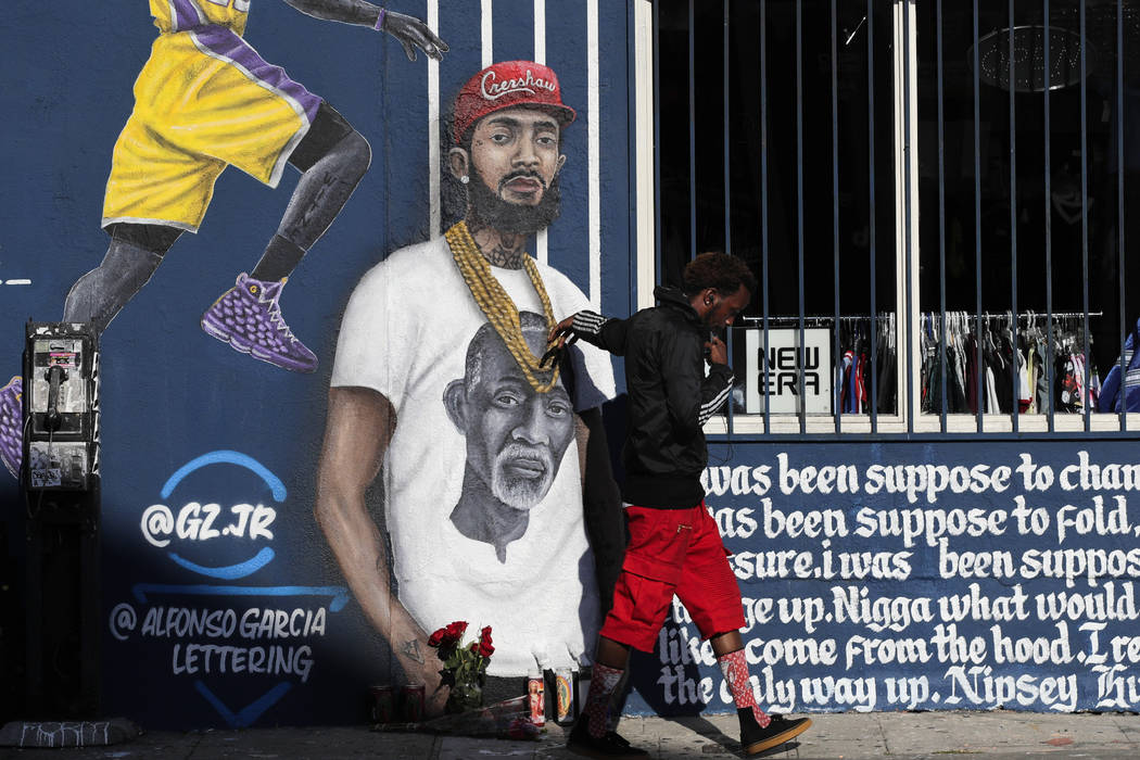 A man touches a mural depicting slain rapper Nipsey Hussle, Tuesday, April 2, 2019, in Los Ange ...