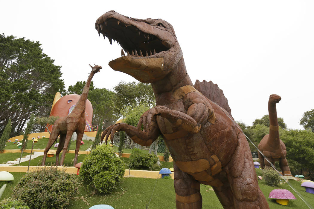 In this photo taken Monday, April 1, 2019, dinosaurs and other figurines stand in the backyard ...