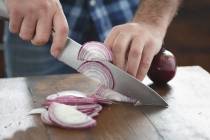 A man chops onions on a table. (Getty Images)
