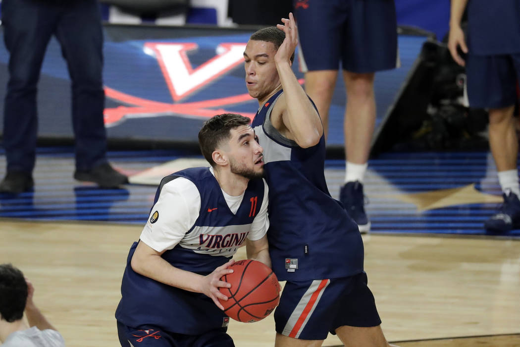 Virginia's Ty Jerome (11) drives against Francesco Badocchi during a practice session for the s ...