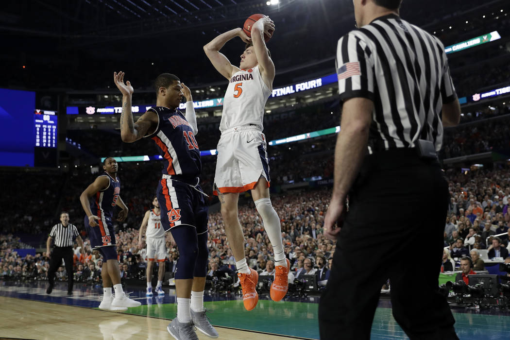 Virginia's Kyle Guy (5) takes a shot as Auburn's Samir Doughty (10) was called foul during the ...