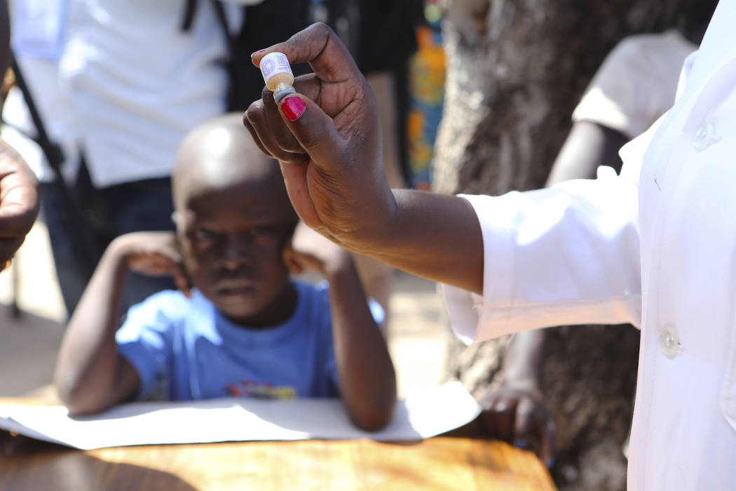 A health worker prepares to administer an oral cholera vaccination to a child at a camp for dis ...