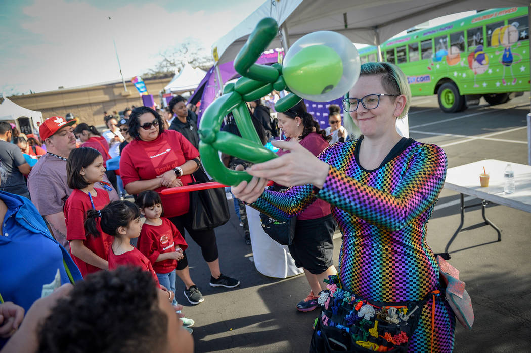 Erika Comparoni from Las Vegas hands a balloon hat to a boy at the 29th Annual AIDS Walk Las Ve ...