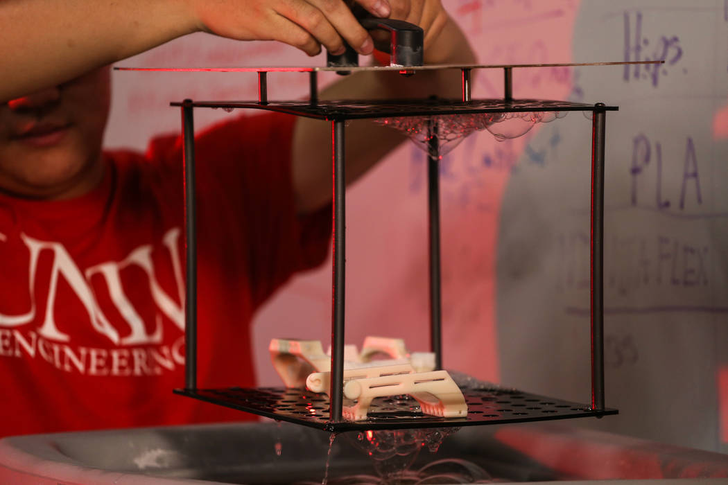 Tian Chen, a mechanical engineering sophomore at UNLV, 20, lifts a 3-D printed prosthetic hand ...