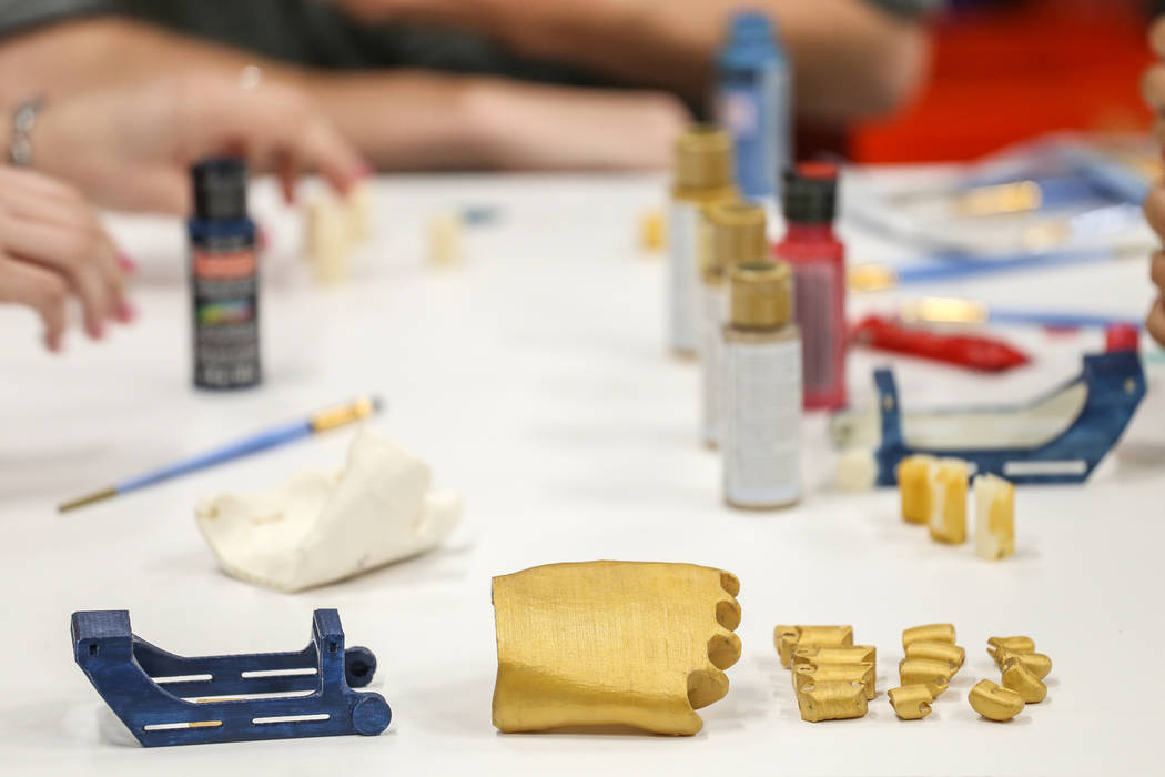 Parts for a 3-D printed prosthetic hand are laid out on a table during a painting process at th ...