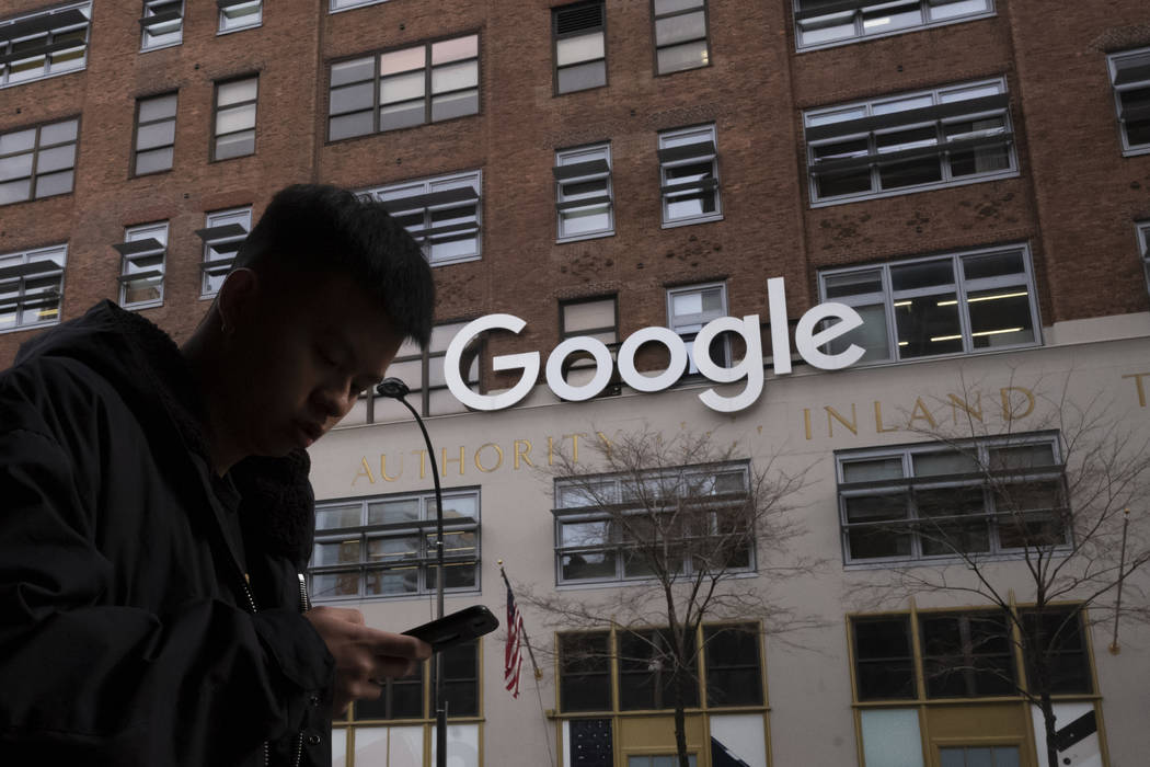 A man using a mobile phone walks past Google offices in New York on Dec. 17,2018. Executives fr ...