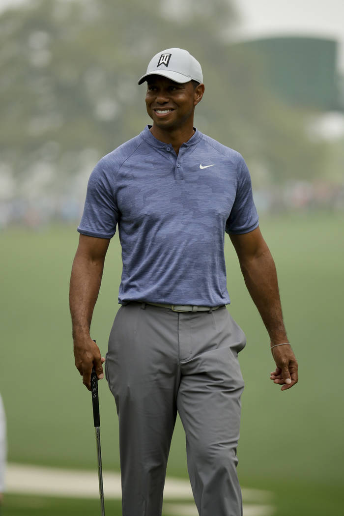 Tiger Woods smiles on the 10th green during a practice round for the Masters golf tournament Mo ...