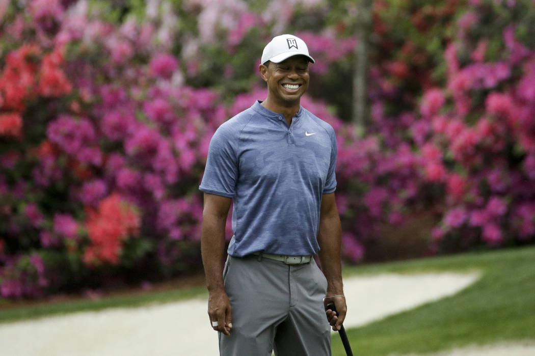 Tiger Woods smiles as he walks off the 13th green during a practice round for the Masters golf ...