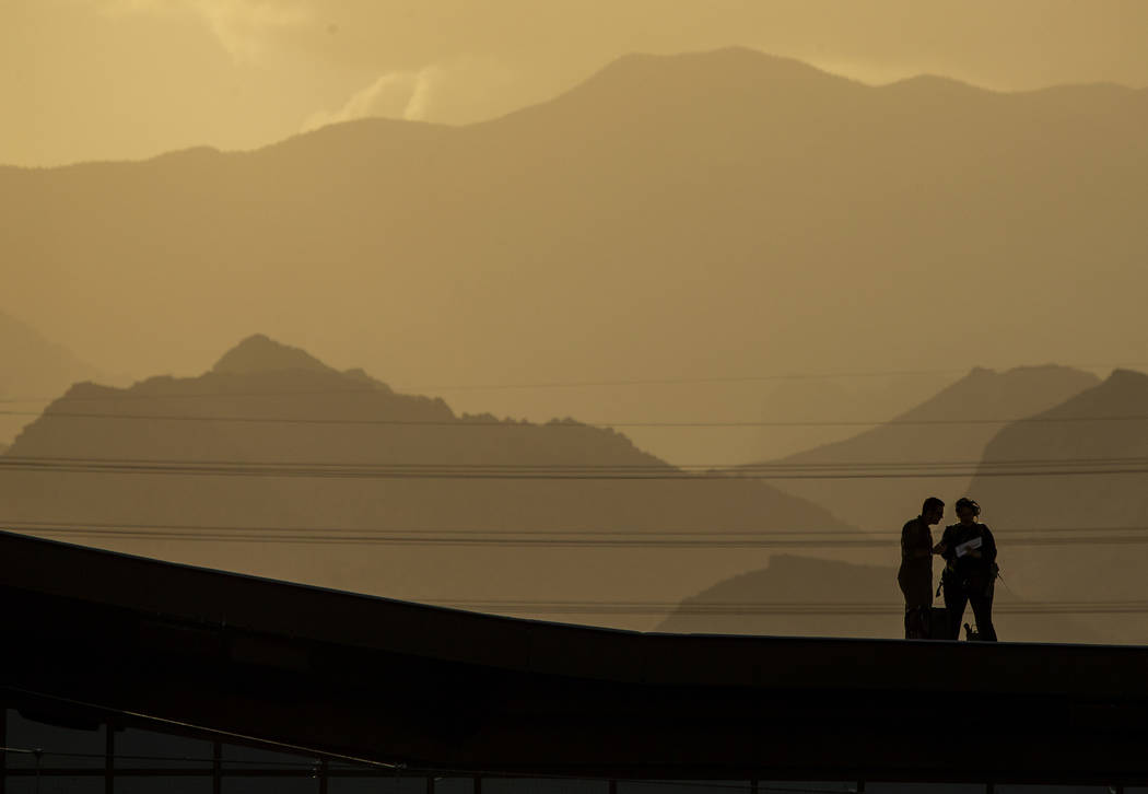 The sun is low on the horizon behind a rooftop crew before the Las Vegas Aviators home opener o ...