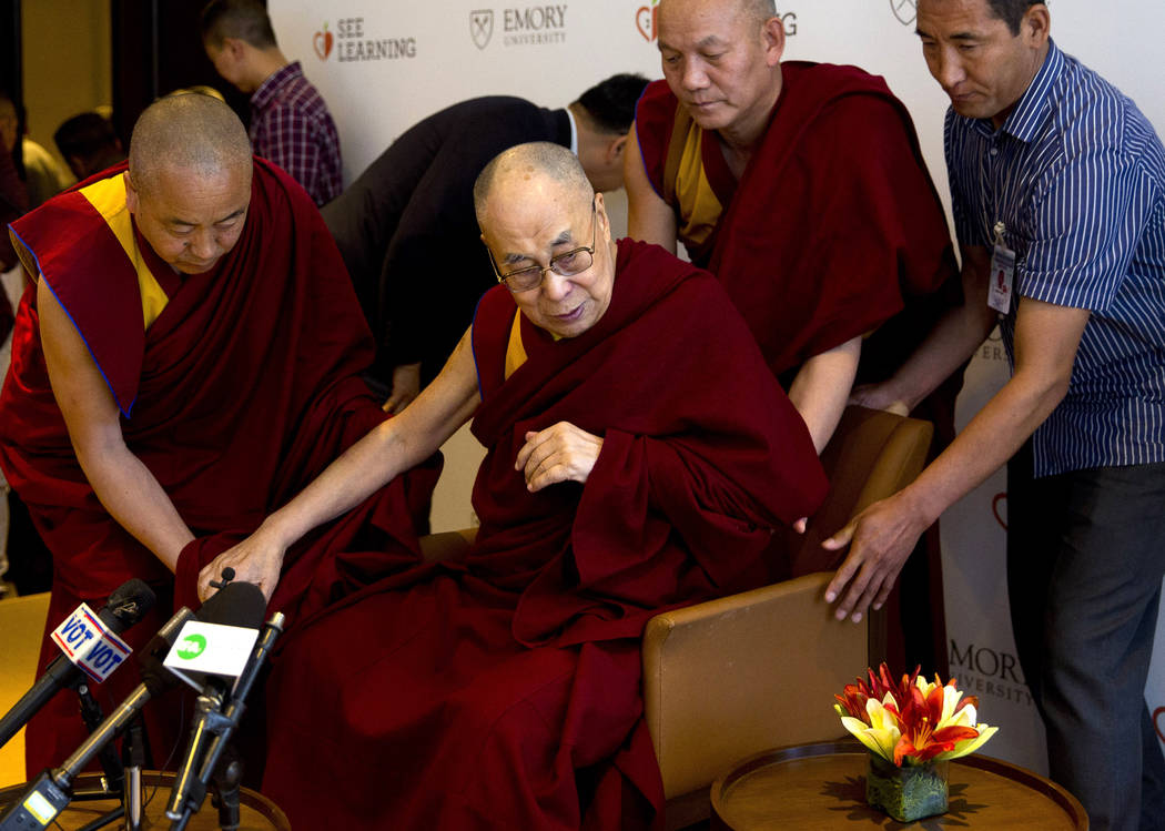 In this April 4, 2019, file photo, Tibetan spiritual leader the Dalai Lama, center, is assisted ...