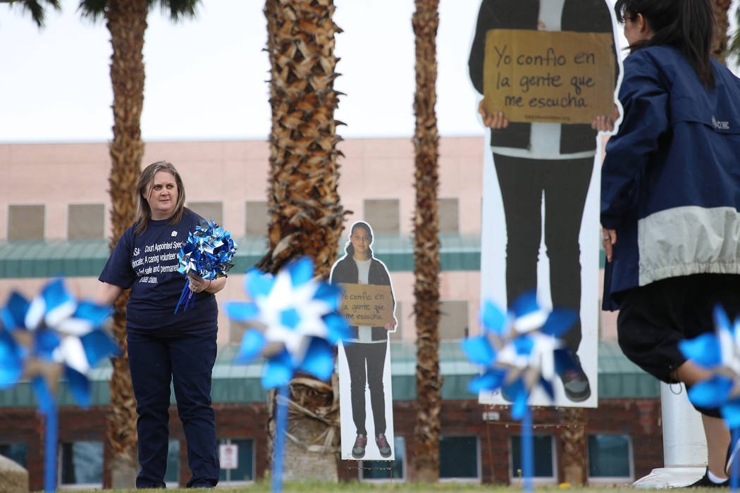 Marci Perea, left, help plant pinwheels outside of the Eighth Judicial District Family Court in ...