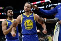 Golden State Warriors guard Stephen Curry (30) is grabbed by teammates as he reacts after being ...