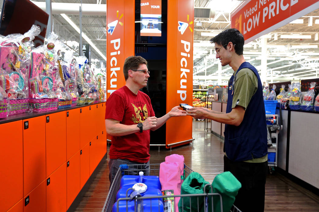 Harold Lloyd signs his order for Walmart Associate Tye Bonilla scan at the pickup tower at the ...