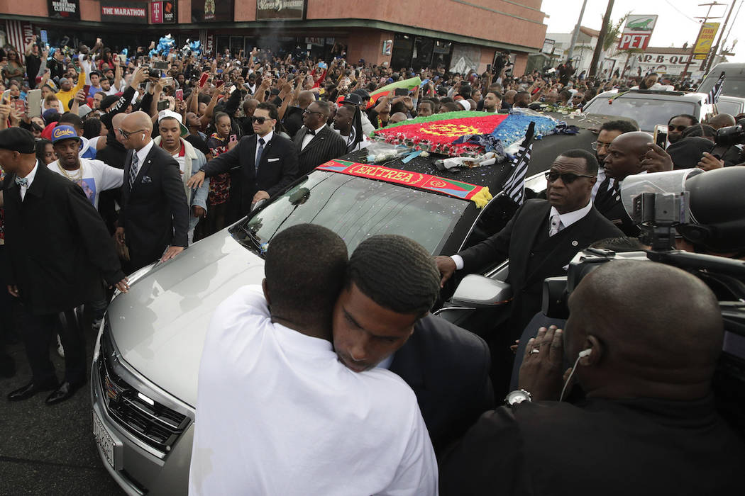 Two men hug as a hearse carrying the casket of slain rapper Nipsey Hussle passes through the cr ...