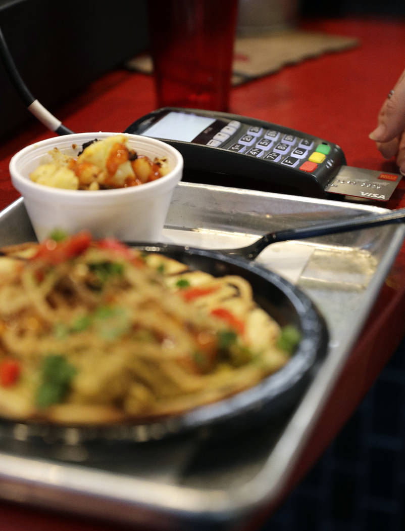 FILE - In this April 10, 2018, file photo, a customers uses a credit card machine to pay for fo ...