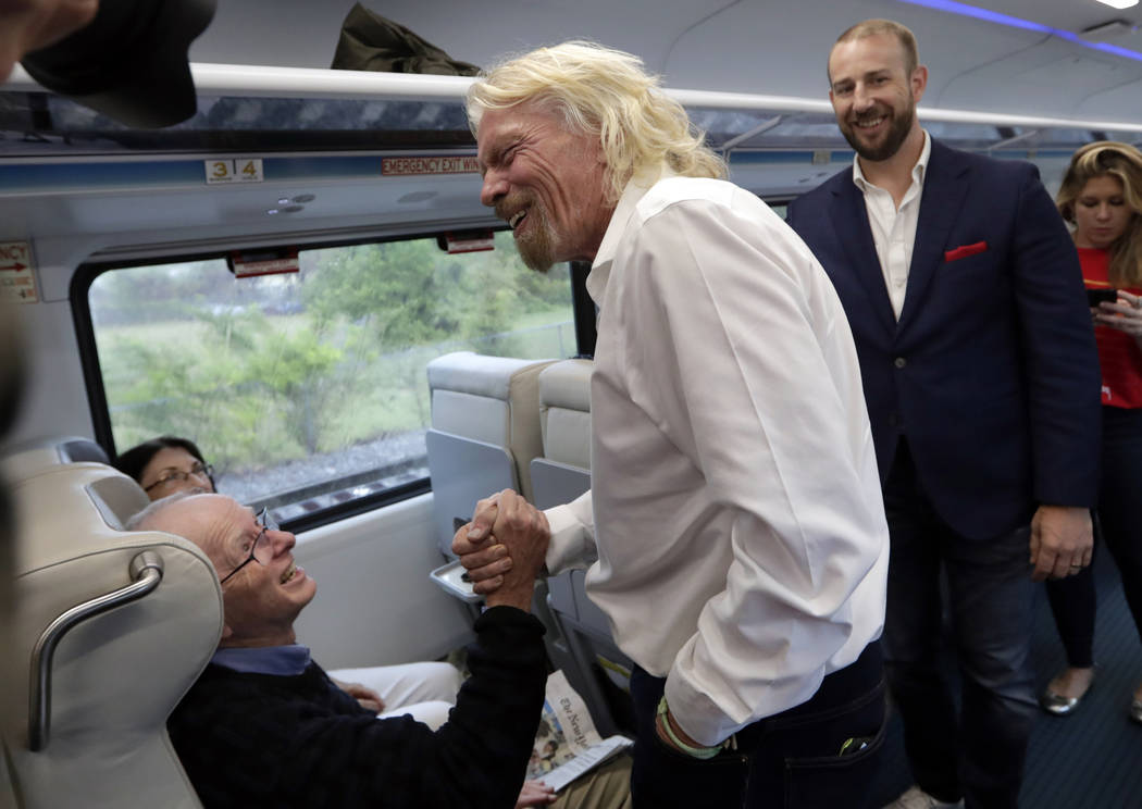 Richard Branson, of Virgin Group, center, greets a passenger while riding a Brightline train fr ...