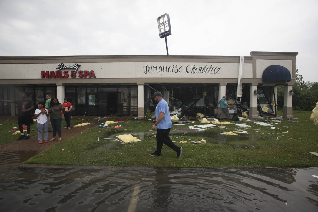 Shop owners and workers stand outside of their shops and walk through debris in the Pemberton Q ...