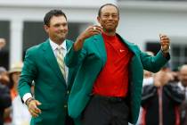 Patrick Reed helps Tiger Woods with his green jacket after Woods won the Masters golf tournamen ...