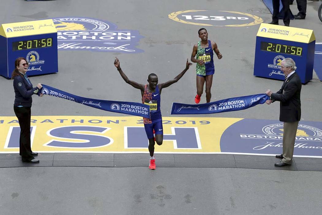 Lawrence Cherono, of Kenya, breaks the tape to win the 123rd Boston Marathon in front of Lelisa ...