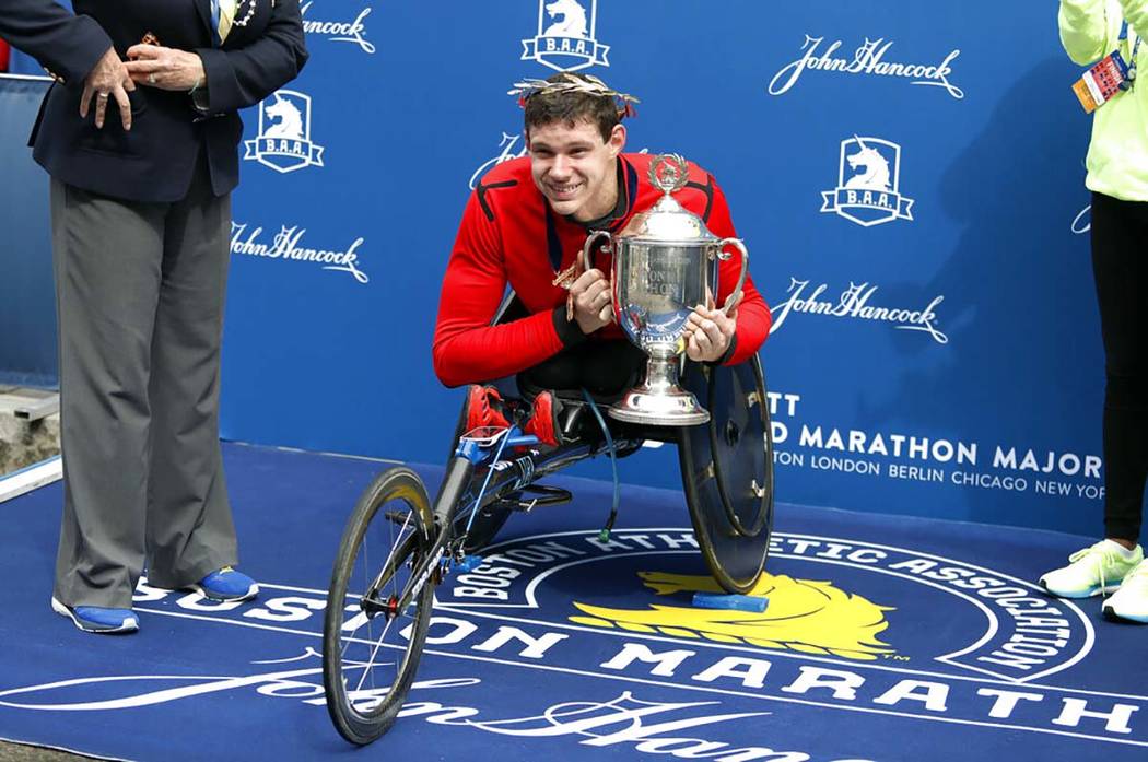 Daniel Romanchuk, of Urbana, Ill., holds the trophy after winning the men's handcycle division ...