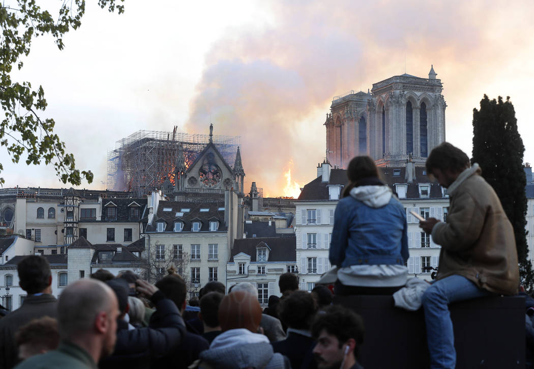 People watch as flames and smoke rise from Notre Dame cathedral as it burns in Paris, Monday, A ...