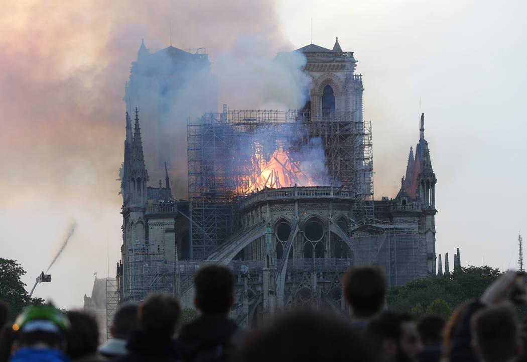 People watch as flames and smoke rise from Notre Dame cathedral as it burns in Paris, Monday, A ...