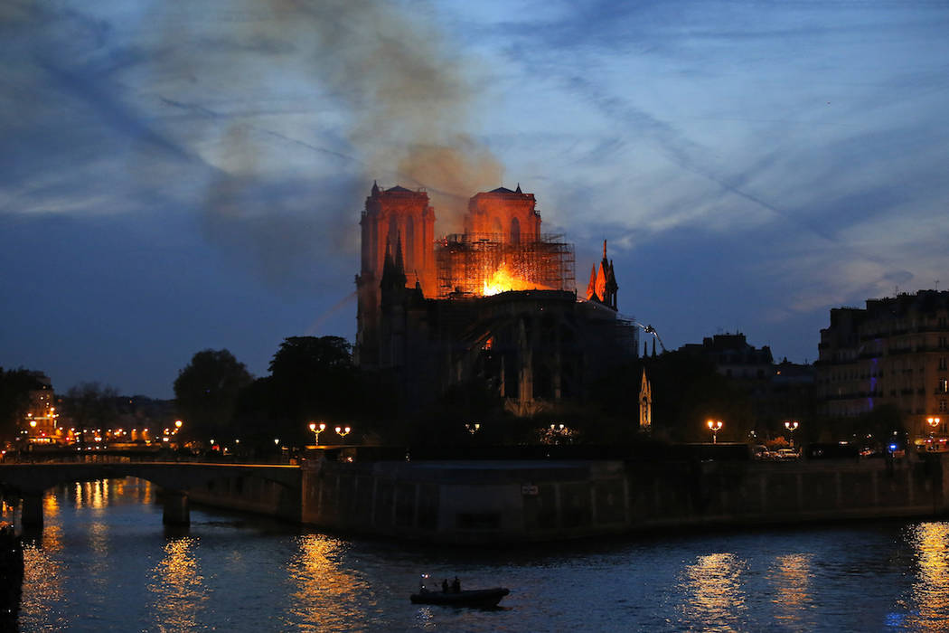 Firefighters tackle the blaze as flames and smoke rise from Notre Dame cathedral as it burns in ...