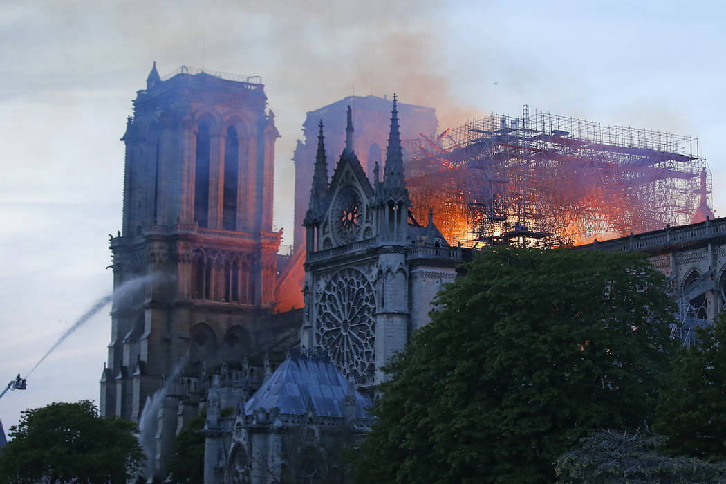 A firefighter tackles the blaze as flames and smoke rise from Notre Dame cathedral as it burns ...