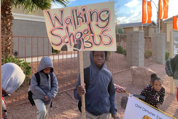 Students walking with Johnson hold signs to let bypassers know they're walking to school. (Mia ...