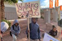Students walking with Johnson hold signs to let bypassers know they're walking to school. (Mia ...