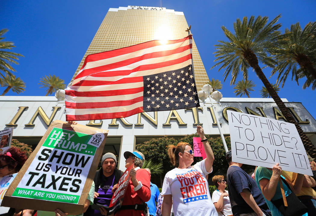 Colleen Brola, center right, holds an upside down American flag during a tax day protest at Tru ...