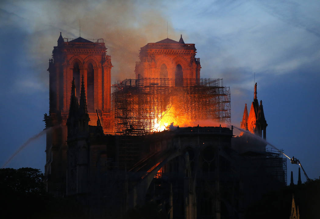 Firefighters tackle the blaze as flames and smoke rise from Notre Dame cathedral as it burns in ...