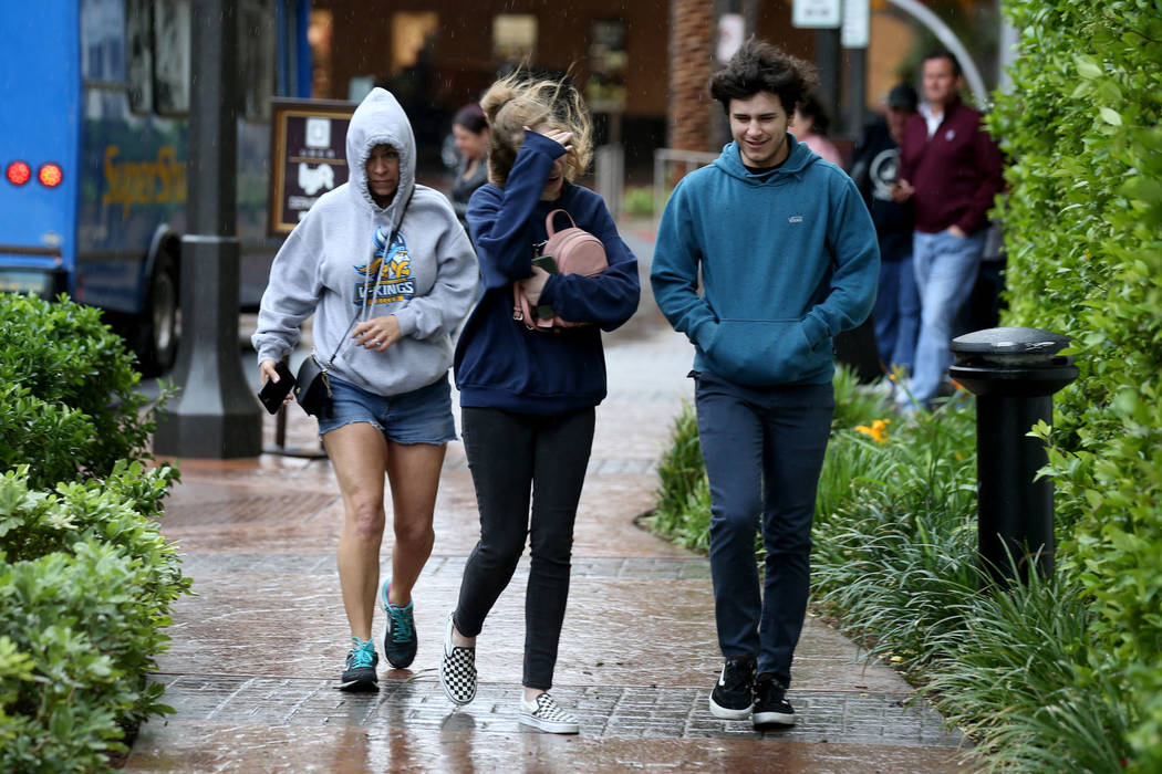 Charli Alu, left, and her children Emilee, 16, and Trevor, 15, make their way through wind and ...